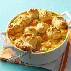 chicken pot pie with biscuits and carrots in a white casserole dish on a blue tablecloth