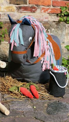 a horse bag sitting on the ground next to some carrots and a toy horse