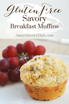 a muffin sitting on top of a white plate next to grapes