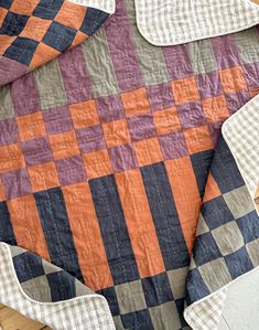 an orange and black quilt on top of a wooden floor