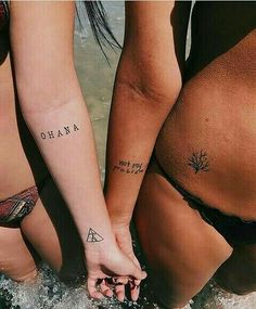 two women in bikinis holding hands while standing in the water with their backs to each other