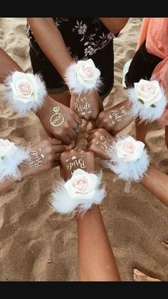 a group of people standing in the sand with their hands on top of each other