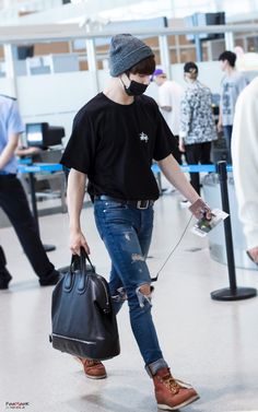 a man wearing a face mask and carrying a black bag while walking through an airport