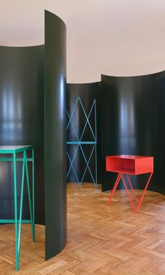 three different colored tables in a room with black walls and wood flooring on the side