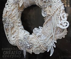 a close up of a wreath on a door with pearls and lace around the wreath