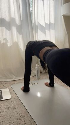 a woman is doing yoga in front of a laptop