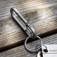 a pair of scissors sitting on top of a wooden table next to a metal keychain