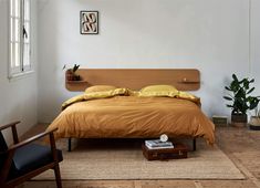 a bed sitting in a bedroom next to a wooden headboard and footstool