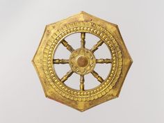 a gold colored clock with four spokes on it