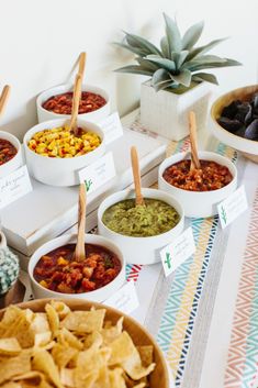 bowls of salsa and tortilla chips are arranged on a table with place cards