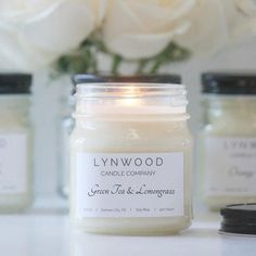 a candle sitting on top of a table next to some white flowers and candles in front of it