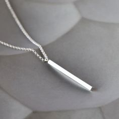 Perfectly straightforward and striking: a solid bar of sterling silver with an integrated loop hangs from a versatile box chain for a geometric statement of simplicity. The silver bar measures 1 3/4 inches long and is 2mm wide (squared). The necklace is finished with a simple silver lobster clasp. Choose your ideal chain length from the drop-down menu, and remember to factor in the length of the pendant to find your perfect necklace (chain length + pendant length). Elegant Silver Rectangular Bar Necklace, Silver Minimalist Necklace With Rectangular Pendant, Classic Silver Bar Necklace, Minimalist Silver Rectangular Pendant Jewelry, Minimalist Silver Rectangular Jewelry, Minimalist Sterling Silver Bar Necklace With Rectangular Pendant, Modern Sterling Silver Bar Necklace, Simple Silver Necklace With Rectangular Pendant, Classic Sterling Silver Bar Necklace