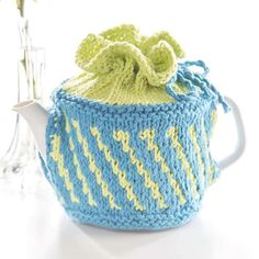 a knitted tea cosy with a flower in it