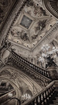 an ornate staircase with chandeliers and paintings on the walls in black and white