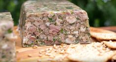 a piece of food sitting on top of a wooden cutting board next to crackers