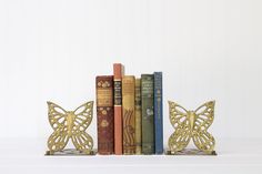 three books are sitting on top of each other in front of a book shelf with gold butterflies