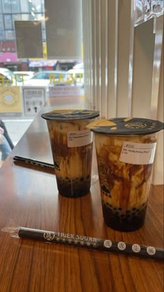 two plastic cups sitting on top of a wooden table