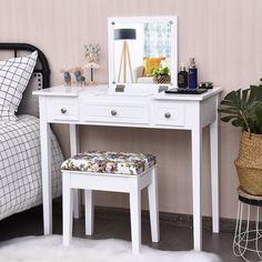 a bedroom with a white vanity table and stool next to a plant on the floor