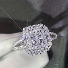 a fancy diamond ring is being held by someone's hand in a white glove