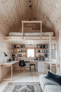 a room with wooden walls and flooring has a couch, desk, bookshelf and chair in it