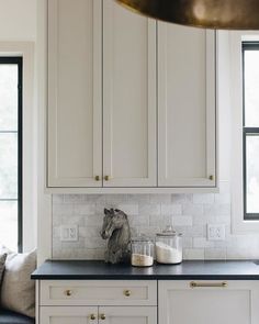 a kitchen with white cabinets and black counter tops in front of two large windows that look out onto the street