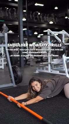 a woman laying on the ground in front of a gym equipment rack with an orange handle