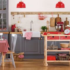 a kitchen filled with lots of wooden furniture and red lights hanging from the overhead cabinets