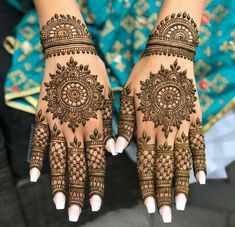 two hands with henna tattoos on them, one is showing off the intricate design