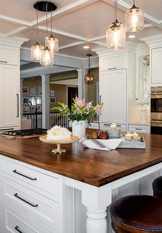 a large kitchen with white cabinets and wooden counter tops, along with two stools