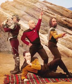 four men in star trek costumes are posing for a photo on a blanket near some rocks