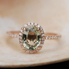 an oval cut green amethorate surrounded by white and brown diamonds on top of a shell