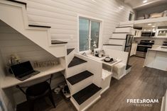 the interior of a tiny home with white walls and wood flooring, including stairs