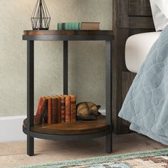 a small table with books on it next to a bed and nightstand in a bedroom