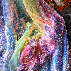 colorful sequins on fabric with flowers in the backgroung and behind it