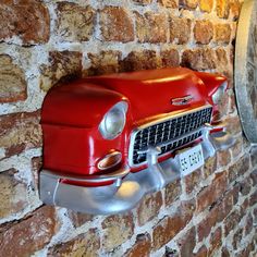 an old red car is mounted to a brick wall