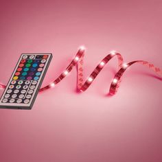 a remote control sitting on top of a pink surface next to a strip of tape