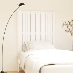 a bedroom with a white bed and a black floor lamp in the corner next to it