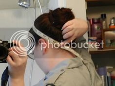 a woman is measuring her hair with a tape