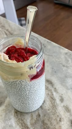 a spoon sticking out of a jar filled with chia seed pudding and strawberry compote