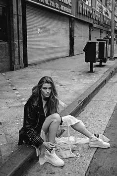 a woman sitting on the curb with her shoes off