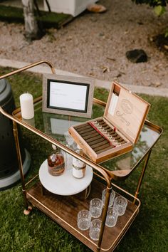 a glass table topped with drinks and an open laptop computer on top of a wooden tray