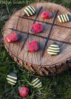 four painted rocks sitting on top of a piece of wood next to each other in the grass