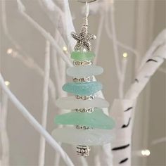 a glass ornament hanging from a tree decorated with seaglass and starfish