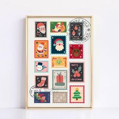 a framed christmas postcard with stamps and santa's stockings on it, in front of a white wall