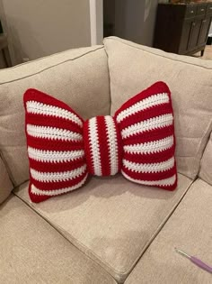 a red and white crocheted bow pillow sitting on top of a couch