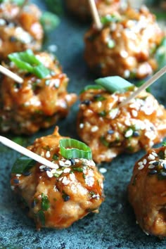 several skewered meatballs with sesame seeds and green onions