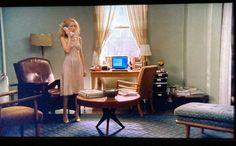 a woman standing in a living room talking on the phone