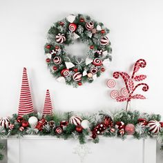 christmas decorations are arranged on the mantle in front of a wreath and candy canes