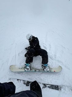 the snowboarder is sitting on his board in the snow