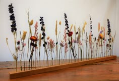 an arrangement of dried flowers on a wooden shelf